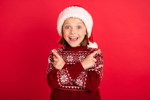 Photo of little girl happy positive smile point fingers empty space ad promo advise christmas season isolated over red color background - Photo, image