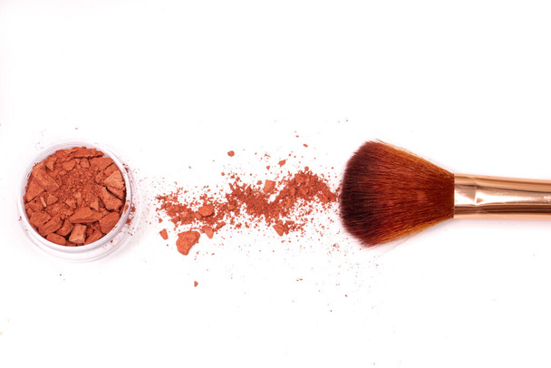 Creative photo of cosmetic swatches. Broken eye shadows in bronze colour and make up brush on a white background  - Φωτογραφία, εικόνα