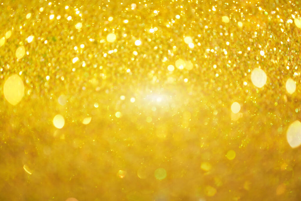 The blurred texture of the golden shine. Background with gold glitter or yellow sequins. Seamless texture with yellow gold sequins. Flickering background. - Foto, afbeelding