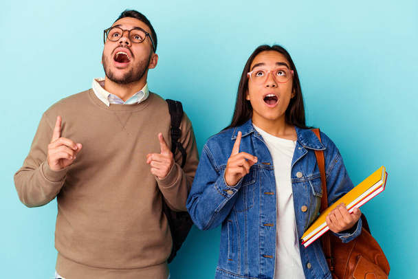 Junge gemischte Rasse Studentenpaar isoliert auf blauem Hintergrund zeigt auf den Kopf mit geöffnetem Mund. - Foto, Bild