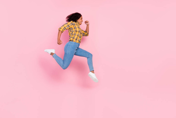 Photo of pretty charming dark skin lady wear checkered shirt jumping running looking empty space smiling isolated pink color background - Φωτογραφία, εικόνα