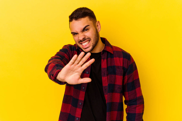 Young caucasian man isolated on yellow background rejecting someone showing a gesture of disgust. - Photo, Image