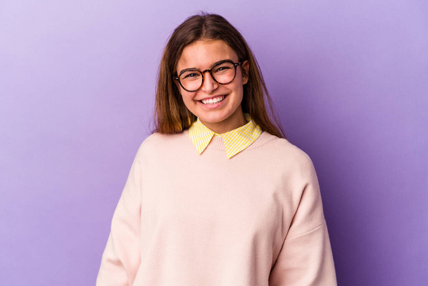Young caucasian woman isolated on purple background happy, smiling and cheerful. - Photo, Image