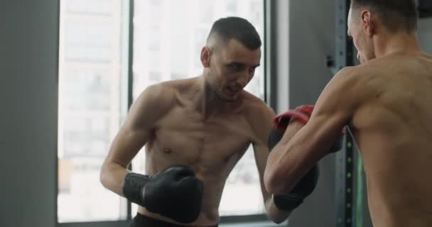 Bojovník v boxerských rukavicích cvičí své údery s trenérem ve zpomaleném filmu v tělocvičně, kickboxeři trénují, 4k 120fps Prores HQ - Záběry, video