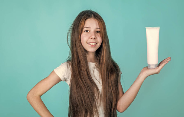 wash and rinse. happy teen girl presenting cosmetic product. shampooing hair in salon. daily habits and personal care. child use cream shampoo in bottle. hair conditioner. beauty nourishing mask - Φωτογραφία, εικόνα