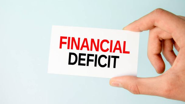 бумажная визитная карточка бизнесмена с текстовым финансовым дефицитом, крупным планом светло-голубого фона, бизнес-концепция - Фото, изображение