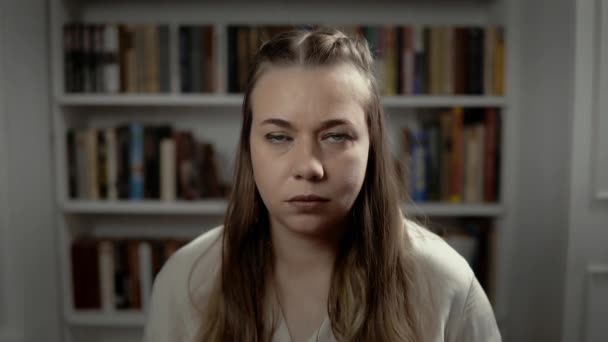 Ritratto di giovane donna seria che chiude la bocca a mano seduta in camera - Filmati, video