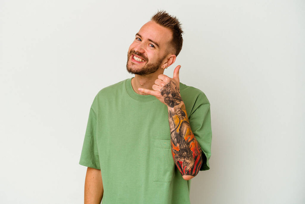 Mladý tetovaný běloch izolovaný na bílém pozadí ukazující gesto mobilního telefonu s prsty. - Fotografie, Obrázek
