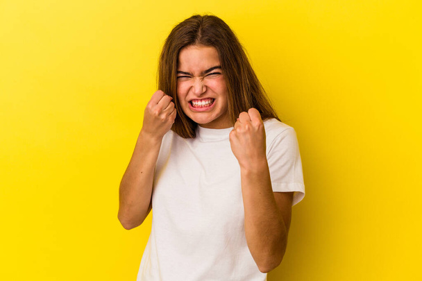 Νεαρή καυκάσια γυναίκα απομονωμένη στο κίτρινο φόντο αναστατωμένη ουρλιάζοντας με τεντωμένα χέρια. - Φωτογραφία, εικόνα