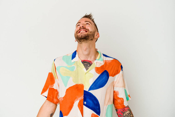 Young tattooed caucasian man isolated on white background relaxed and happy laughing, neck stretched showing teeth. - Photo, Image