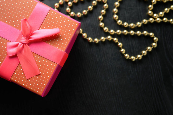 beautiful gift wrapped with festive ribbon on a black wooden background - 写真・画像