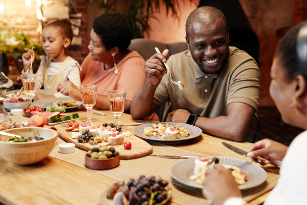 Sorridente uomo afroamericano a cena in famiglia - Foto, immagini