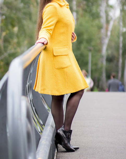 Sarı ceketli bir kız parkta yürüyor. Parkta dinlen. - Fotoğraf, Görsel