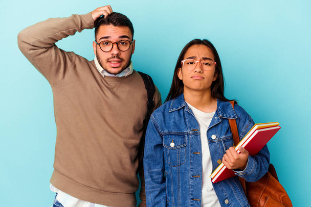 Junge gemischte Rasse Studentenpaar isoliert auf blauem Hintergrund schockiert, sie erinnert sich an wichtiges Treffen. - Foto, Bild