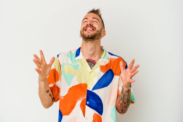 Young tattooed caucasian man isolated on white background laughs out loudly keeping hand on chest. - Photo, Image