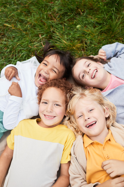 Lachende kinderen liggend op gras - Foto, afbeelding