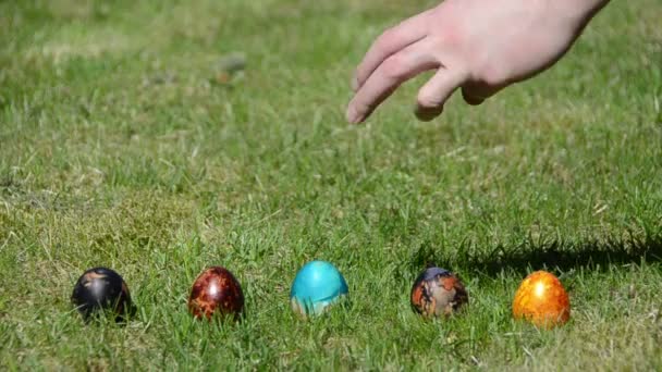 familie Pasen spel met beschilderde kleurrijke eieren op gras. - Video