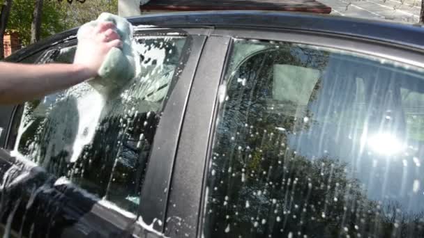 closeup του χεριού με το σαπωνώδες σφουγγάρι καθαρίσει πλυσίματος αυτοκινήτων γυαλί - Πλάνα, βίντεο