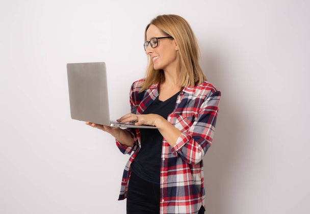 Giovane donna felice sorridente in abiti casual che tiene il computer portatile su sfondo bianco. - Foto, immagini