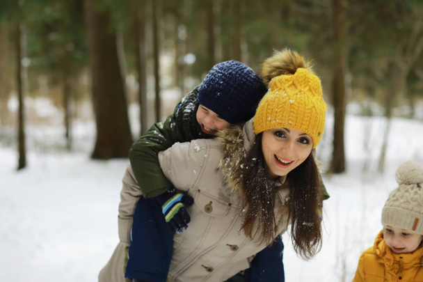 Familia feliz jugando y riendo en invierno al aire libre en la nieve. Parque de la ciudad día de invierno. - Foto, imagen