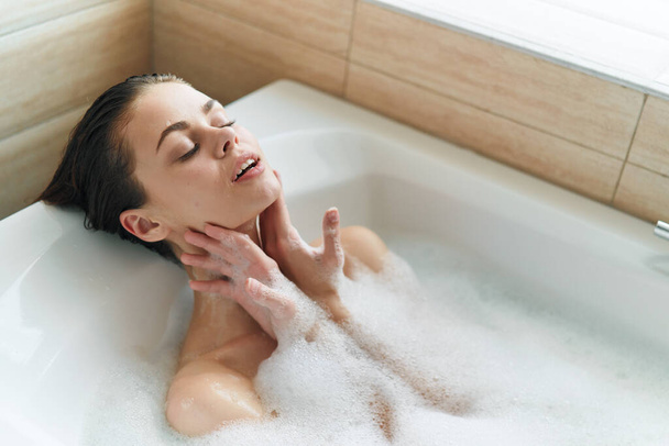 femme reposant dans la baignoire mousse blanche peau propre yeux fermés modèle - Photo, image