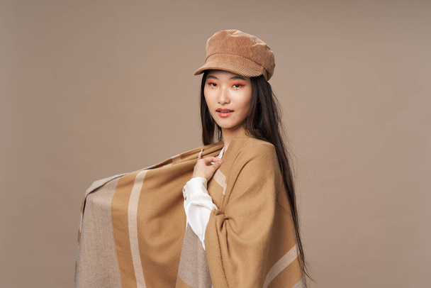 Frau in Hemd und beigem Umhang Hut auf dem Kopf brünette asiatische Erscheinung - Foto, Bild