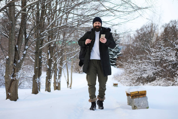 Bearded man in the winter woods. Attractive happy young man with beard walk in park. - Photo, Image