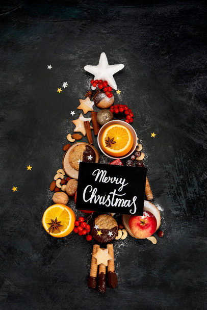Christmas tree made of food on dark background. Festive composition. Top view, copy space - Φωτογραφία, εικόνα