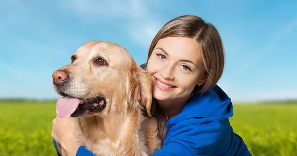 Portrait of beautiful girl petting and hugging dog outdoors. - 写真・画像