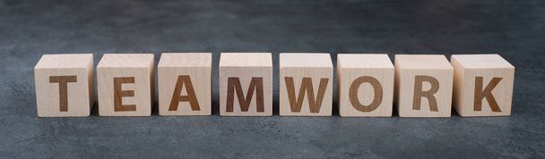 The word teamwork is standing on wooden cubes, dark background - Fotografie, Obrázek