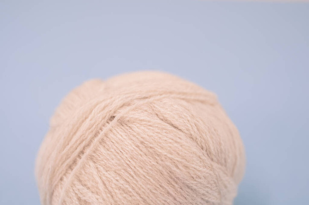 A vertical shot of isolated beige yarn on a blue background with text space - Φωτογραφία, εικόνα