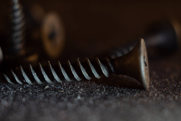 A macro shot of a black rusty solid nail on the ground with a blurry background - Fotoğraf, Görsel