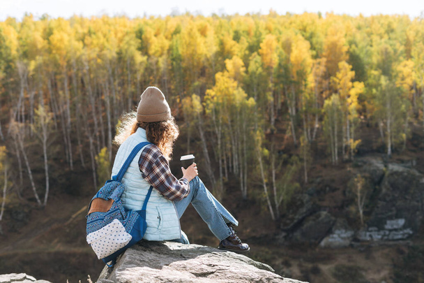 Mulher bonita nova com cabelo encaracolado em camisa xadrez, jeans olha para a vista mágica das montanhas e do rio, caminhadas na natureza outono - Foto, Imagem