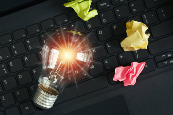 明るい光フレアとキーボードのラップトップ上の電球。創造的なイノベーションを考えてください。eビジネスのオンラインブレインストーミング、ビジョンとアイデアの概念. - 写真・画像