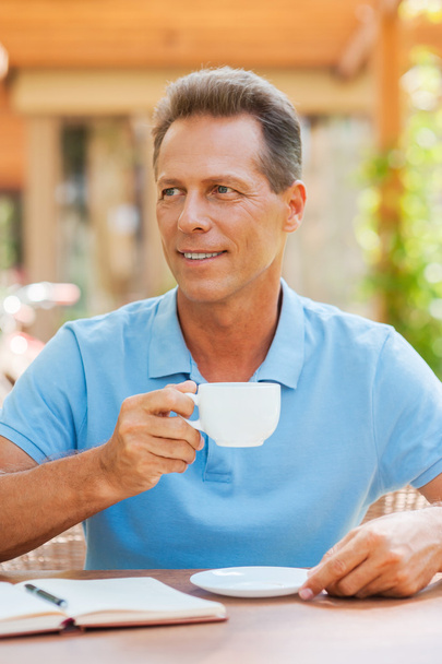 Зрілий чоловік п'є каву на відкритому повітрі
 - Фото, зображення