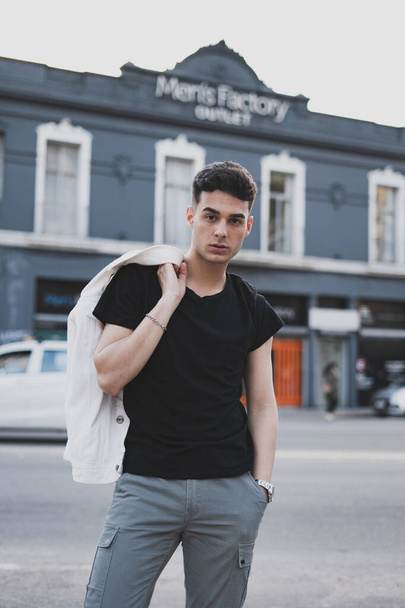 A vertical shot of a young stylish caucasian man in a black t-shirt posing outdoor - Foto, immagini