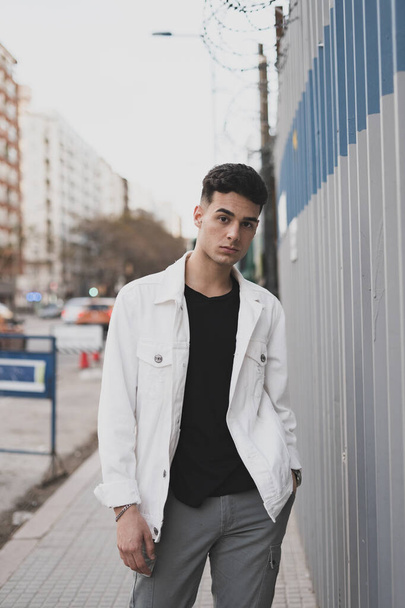 A vertical shot of a young stylish male in a white t-shirt posing on the street - Fotoğraf, Görsel