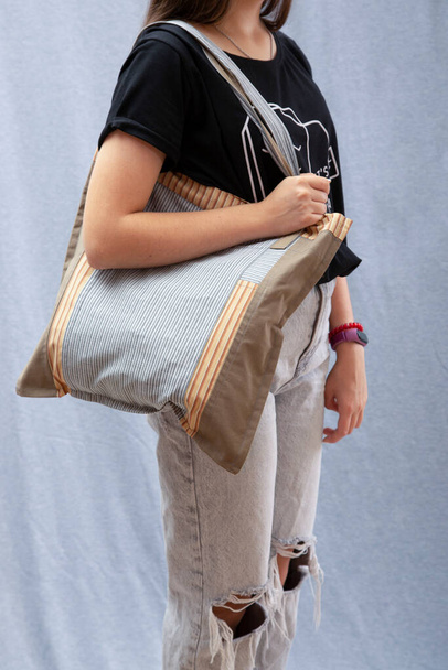 Ein Mädchen hält eine wiederverwendbare Öko-Tasche aus natürlichen Stoffen in der Hand - Foto, Bild