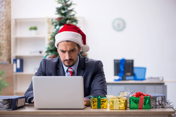 Young male employee celebrating Christmas at workplace - Foto, Imagen