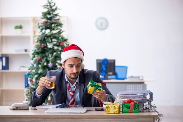 Młody pracownik świętuje Boże Narodzenie w miejscu pracy - Zdjęcie, obraz