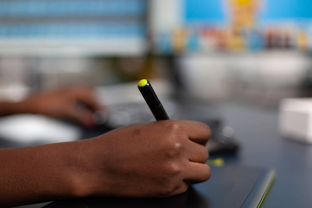 Κοντινό πλάνο του αφρικανού φωτογράφου κρατώντας γραφίδα στυλό επεξεργασία δημιουργική φωτογραφία χρησιμοποιώντας υπολογιστή - Φωτογραφία, εικόνα