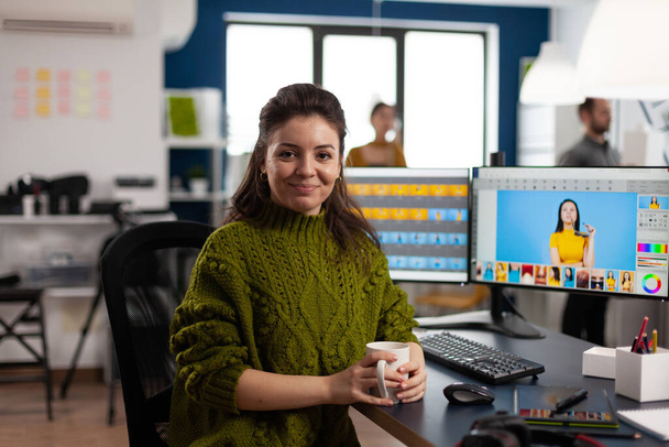 Vrouw retoucher kijkend naar camera lachend zittend in creatief design media bureau - Foto, afbeelding