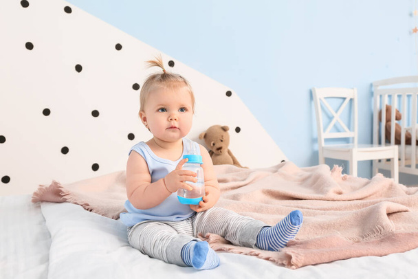 Cute baby girl z butelką wody w sypialni - Zdjęcie, obraz