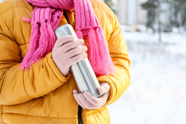 Karlı bir günde termoslu genç bir kadın, yakın plan. - Fotoğraf, Görsel