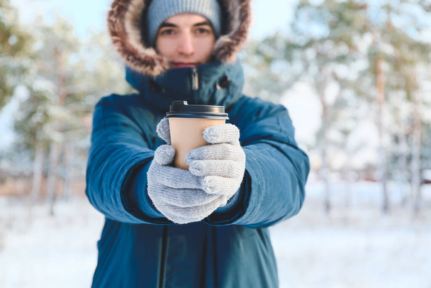 Young man with cup of hot tea on snowy day, closeup - 写真・画像