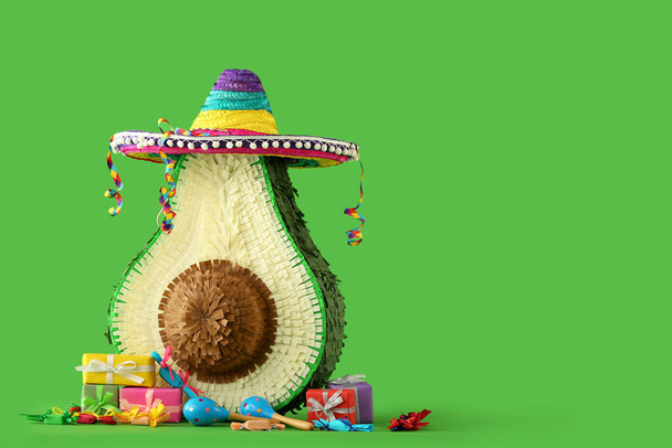 Мексиканская пиньята в сомбреро шляпа, маракасы и подарки на зеленом фоне - Фото, изображение