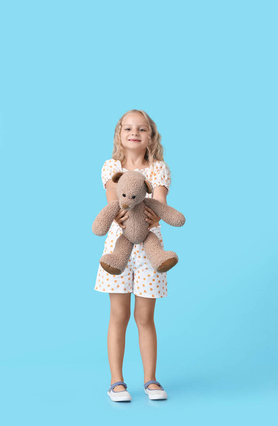 Cute little girl with toy bear on color background - Foto, Imagen