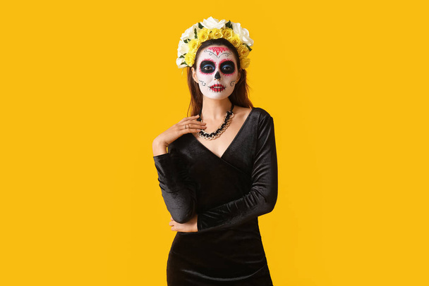 Nuori nainen, jolla on maalattu kallo kasvoillaan väritaustaa vasten. Meksikon kuolleiden päivän juhla (El Dia de Muertos) - Valokuva, kuva