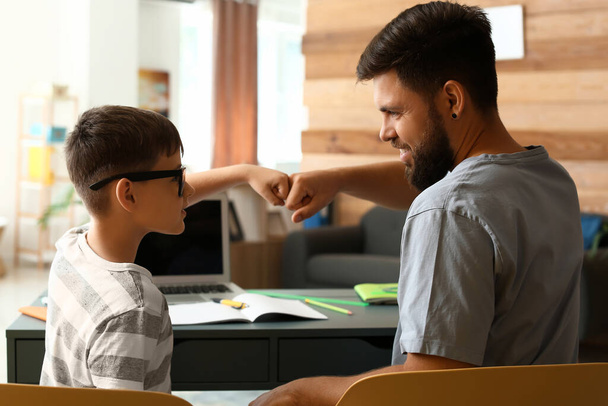 Kleine jongen met zijn vader die thuis les geeft - Foto, afbeelding