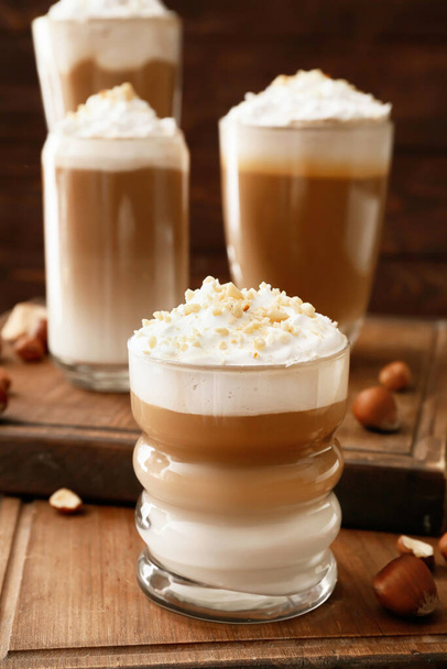 Glasses of tasty latte with nuts on wooden background - Foto, Imagem